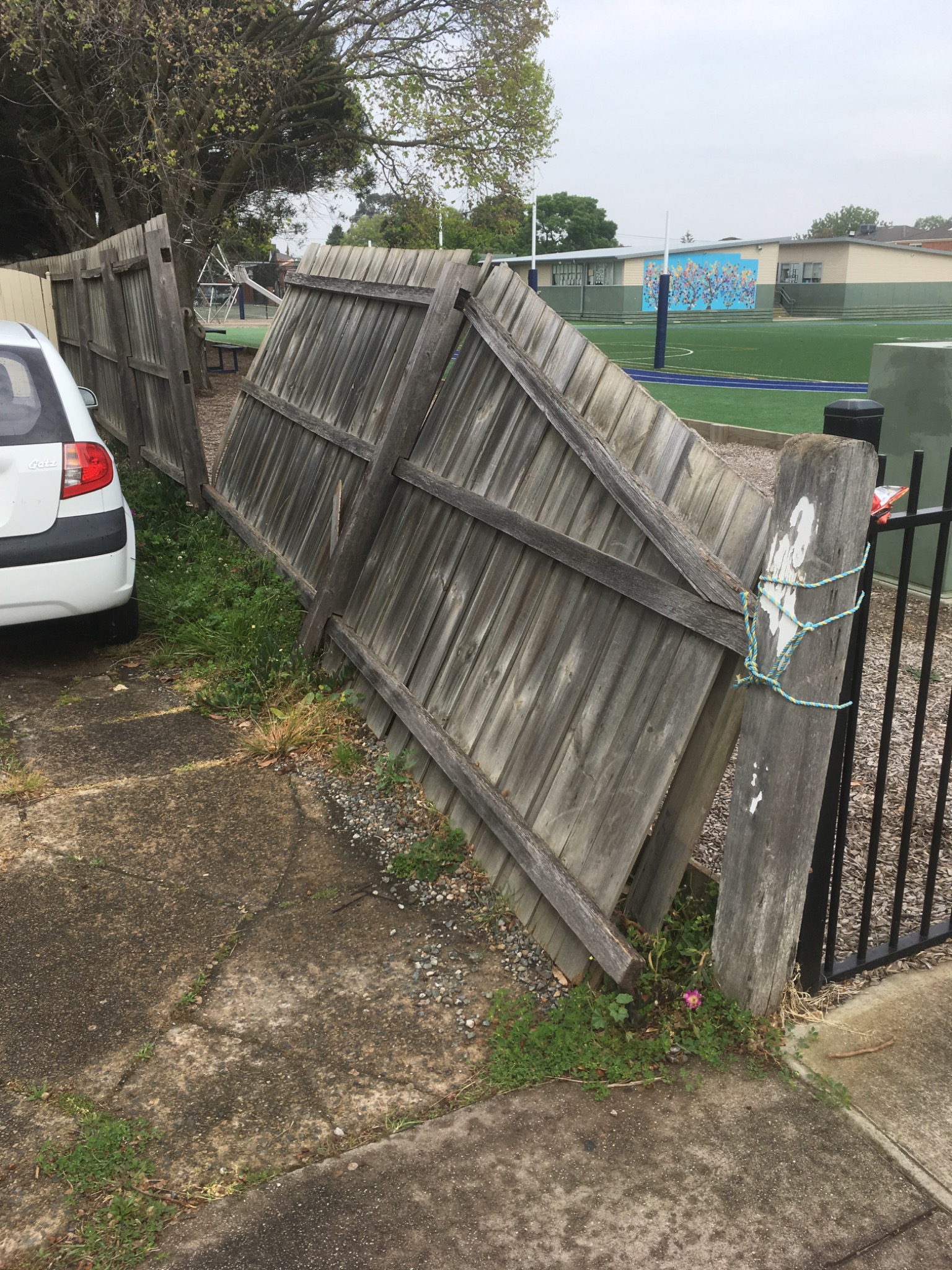 Damaged leaning timber fence before repair in Melbourne